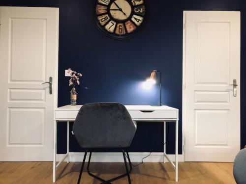 a desk with a chair and a clock on a wall at Hotel restaurant LA PLACE in Saint-Amand-Montrond
