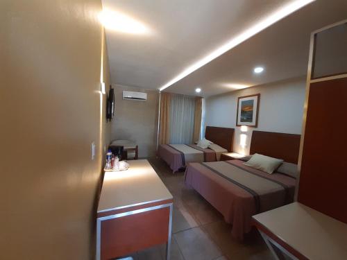 a hotel room with two beds and a desk at HOTEL MARIA TERESA in Playa Azul