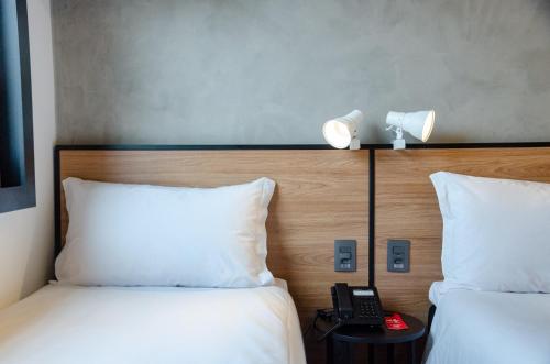 a hotel room with two beds and a phone on a table at ibis Ponta Grossa in Ponta Grossa
