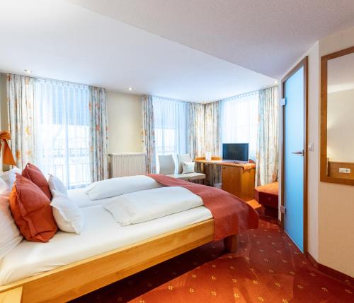 a hotel room with a large bed and a desk at Hotel Zum Ochsen in Schonwald im Schwarzwald