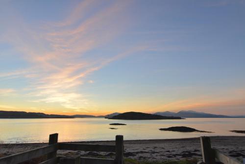 a sunset over a beach with a fence at Witchwood House in Oban
