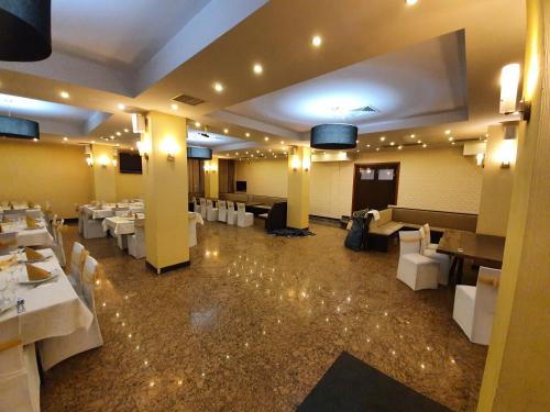 Un comedor con mesas blancas y sillas blancas. en Merion, en Gherla