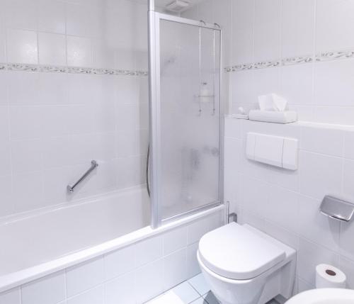 a white bathroom with a toilet and a shower at Hotel Zum Ochsen in Schonwald im Schwarzwald