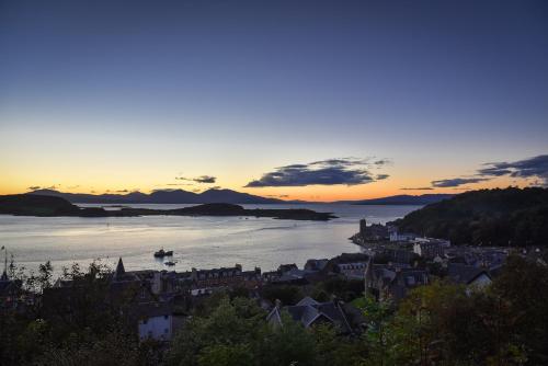 a view of a city with the sun setting over the water at Witchwood House in Oban