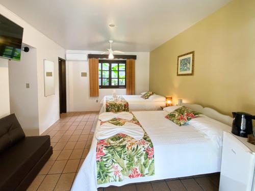 a room with two beds and a couch at Ala Moana Pousada in Bombinhas