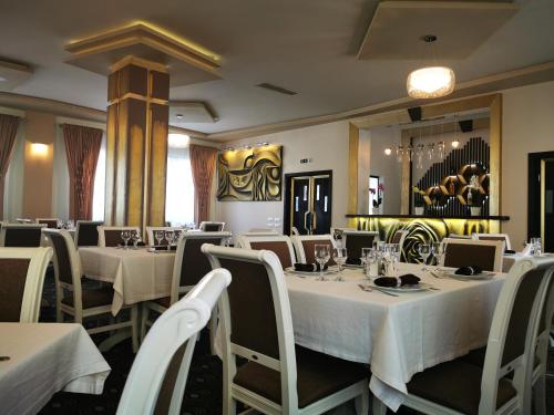 uma sala de jantar com mesas e cadeiras brancas em Amso Residence em Sibiu