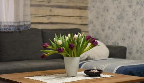 a white vase with purple flowers on a table at Paju Apartement with Sauna in Võru
