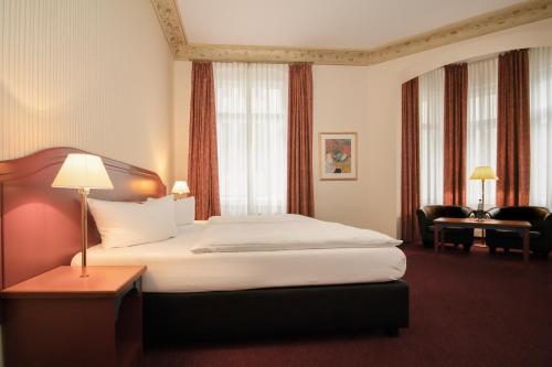 una habitación de hotel con una cama grande y una silla en Akzent Hotel Am Goldenen Strauss, en Görlitz