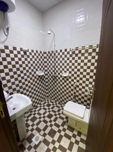 a checkered bathroom with a toilet and a sink at RED-20 - Tag Salalah in Salalah