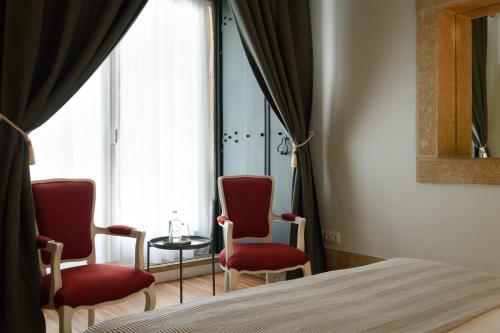 a bedroom with two chairs and a table and a bed at Alecrim ao Chiado in Lisbon