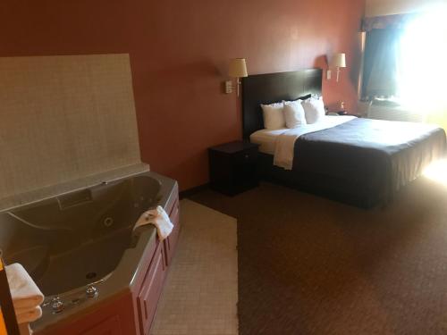a hotel room with a bed and a bath tub at Shary Inn and Suites in Mission