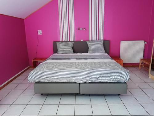 a bedroom with a large bed with pink walls at Hotel Dry Les Courtis in Robertville