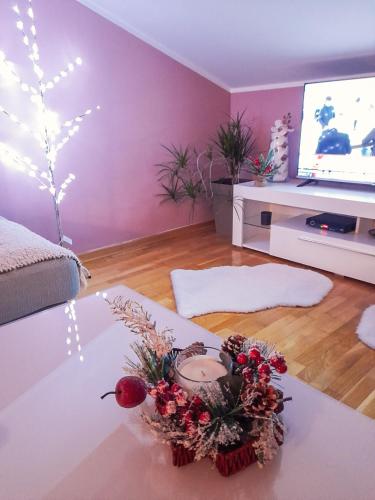 a living room with a table and a tv at Apartman Japanski vrt, Centar in Vrnjačka Banja