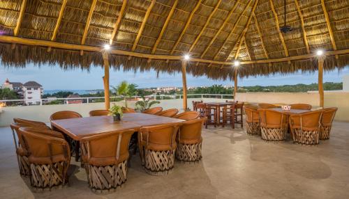 un restaurante con mesas y sillas bajo una sombrilla grande en Punto Mita Suites en Punta Mita