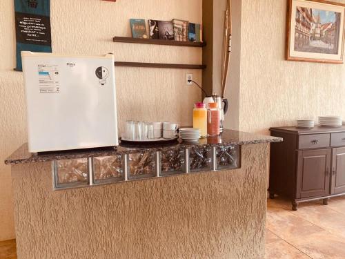 um balcão de cozinha com frigorífico e pratos em Pousada Na Beira do Mar em Baía da Traição