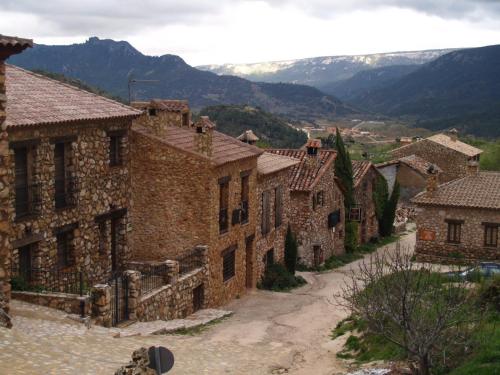 Casa Rural Campoamor في ريوبار: قريه حجريه قديمه مع جبال في الخلف
