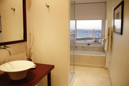 a bathroom with a sink and a tub and a window at Hotel Territorio in Puerto Madryn