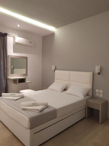 a bedroom with a large white bed with a mirror at Hotel Paraktio in Nea Kalikratia