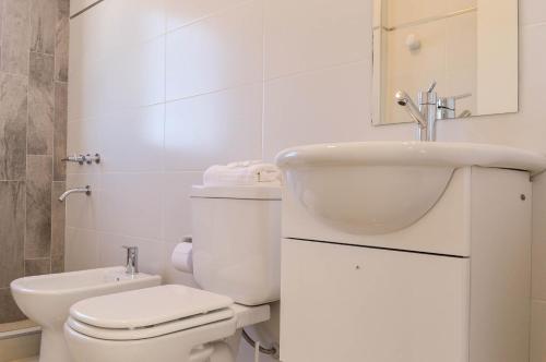 a white bathroom with a toilet and a sink at Live Inn Neuquen in Neuquén