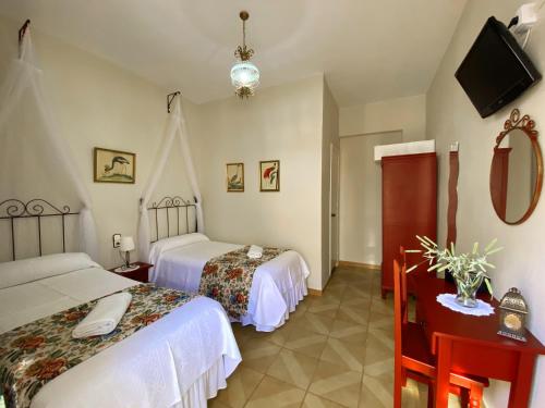 a hotel room with two beds and a television at Pensión Cristina in El Rocío