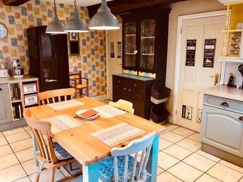 une cuisine avec une table en bois et quelques chaises dans l'établissement Maison Mai or La Petite Maison Mai or La Petite Grange or ALL three, à La Chapelle-Urée