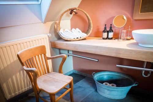 een badkamer met een houten stoel en een wastafel bij B&B Buytenshuys in Hooglede