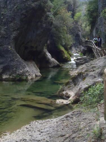 a bridge over a river with people walking on it at Complejo Residencial Los Enebros in Arroyo Frio