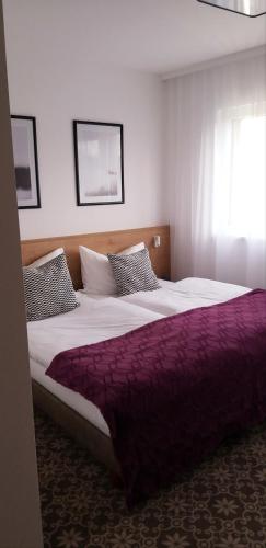 a bedroom with a large bed with a purple blanket at Haidinger's Boutique Domizil in Oftering