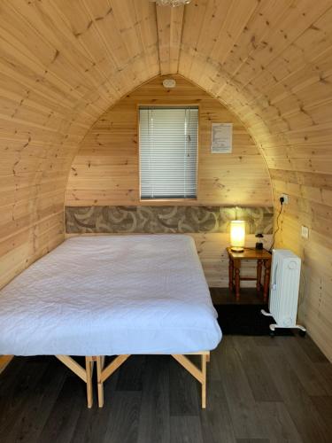 Poplars Farm Site Glamping Pods في Hulland: غرفة نوم بسرير كبير في غرفة خشبية