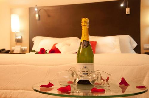 Hotel San Silvestre في بارانكابيرميخا: زجاجة من الشمبانيا وكأسين على طاولة في غرفة الفندق