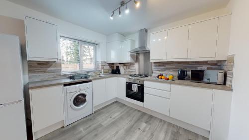 a kitchen with white cabinets and a washer and dryer at Spacious 2 Bedroom Corporate Apartment by Srk Serviced Accommodation in Eye