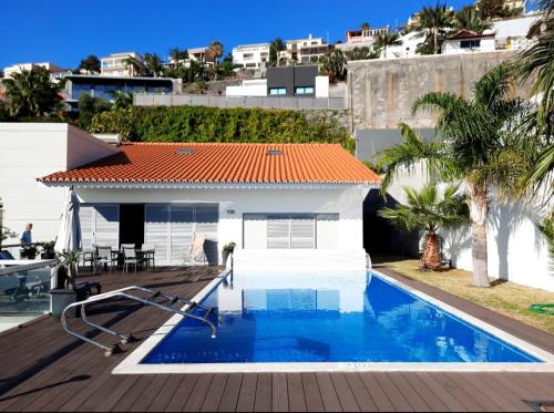 a swimming pool in front of a house at Villa Sol e Mar Garajau Madeira in Caniço