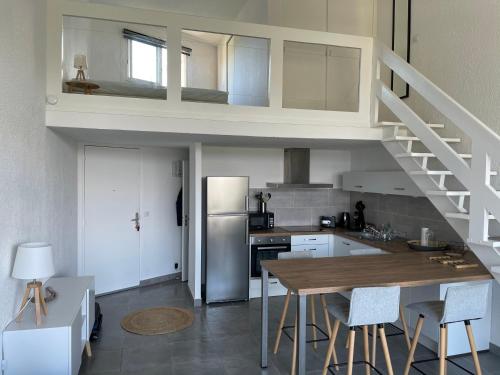 une cuisine avec un lit en mezzanine et une table avec des chaises dans l'établissement duplex vue mer exceptionnelle, à Porticcio