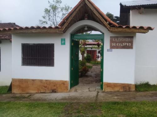 a white building with a green door and a sign at La Posada de Cuispes in Cuispes