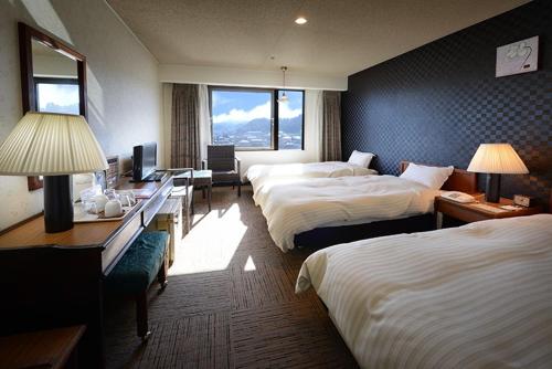a hotel room with two beds and a desk at Hotel Sun Hitoyoshi in Hitoyoshi