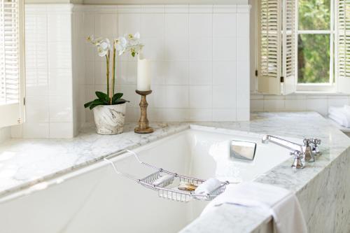 a white bathroom with a tub and a candle at The Willcox in Aiken