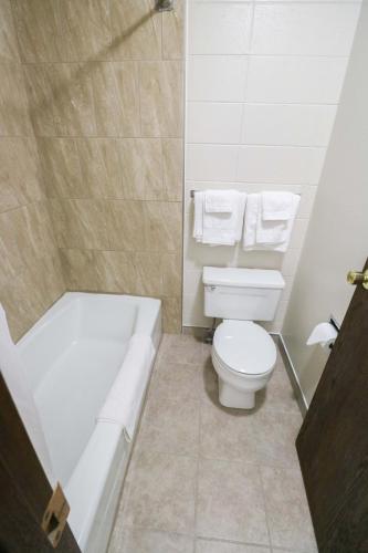 a bathroom with a tub and a toilet and a bath tub at Bear Lodge Motel in Sundance