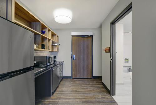a kitchen with stainless steel appliances and a wooden door at Candlewood Suites - Kingston West by IHG in Kingston