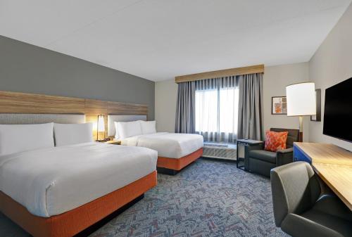a hotel room with two beds and a flat screen tv at Candlewood Suites - Kingston West by IHG in Kingston