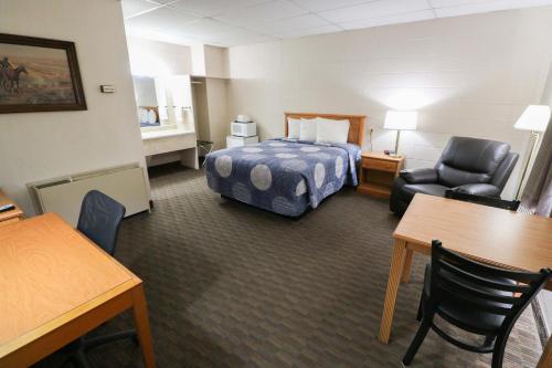 a hotel room with a bed and a chair at Bear Lodge Motel in Sundance