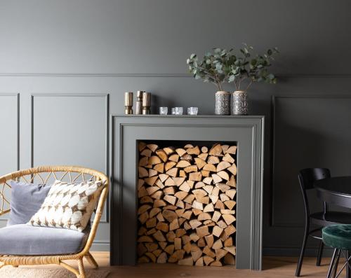 a fireplace filled with fire wood next to a chair at INNI - Boutique apartments in Hveragerði