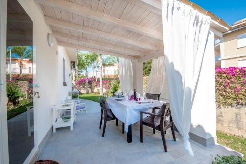 a patio with a white table and chairs on it at Holiday Fontane Bianche Gabriella in Fontane Bianche