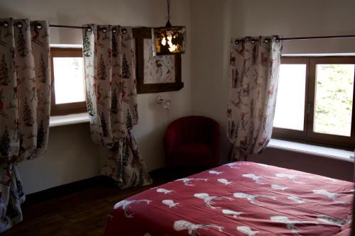 a bedroom with a bed and two windows at Rifugio Baita Gimont in Cesana Torinese