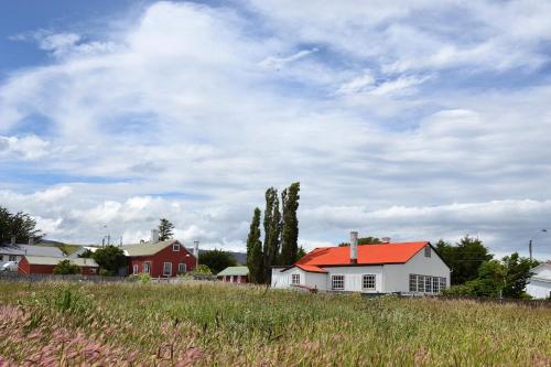 a white house with an orange roof in a field at Puerto Bories House, Country Houses in Patagonia in Puerto Natales