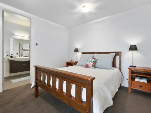 a bedroom with a wooden bed and a mirror at Lake Avenue Studio in Queenstown