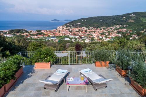 a patio with two chairs and a table and a city at Borgo dell'Uccellaia - Turchese - Giada in Marciana Marina