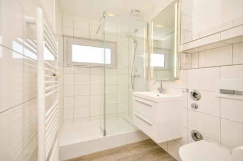 a white bathroom with a shower and a sink at Haus Meeresrauschen Sansibar in Scharbeutz