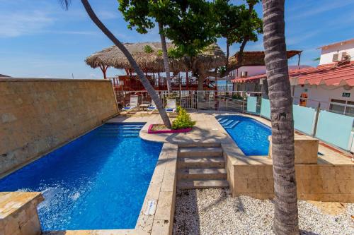 una piscina con palmeras junto a un edificio en GIO Hotel Tama Santa Marta, en Santa Marta