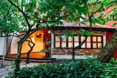 uma casa com uma porta vermelha e algumas árvores em Pousada Fruta Pão em Barra Grande