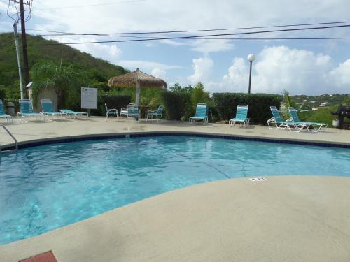 a large swimming pool with chairs and a umbrella at Sapphire Village Condos in St Thomas